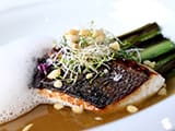 Bar r&ocirc;ti, &eacute;cume d'hu&icirc;tres, poireaux grill&eacute;s et bouillon de fenouil