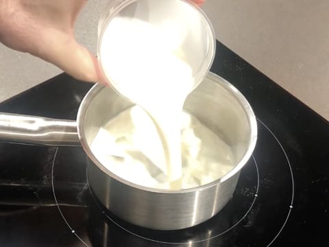 Le lait est versé dans une casserole qui est placée sur la plaque de cuisson