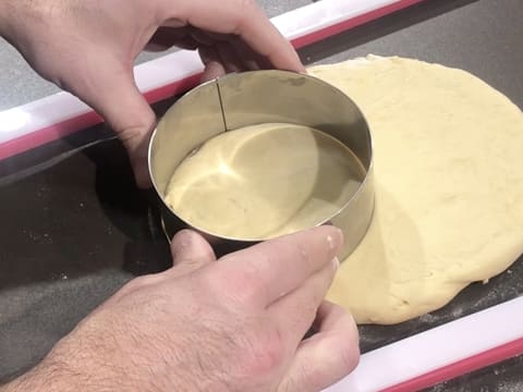 Un cercle à mousse est posé sur l'abaisse de pâte à beignets