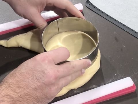 Un cercle à mousse est posé sur l'abaisse de pâte à beignets