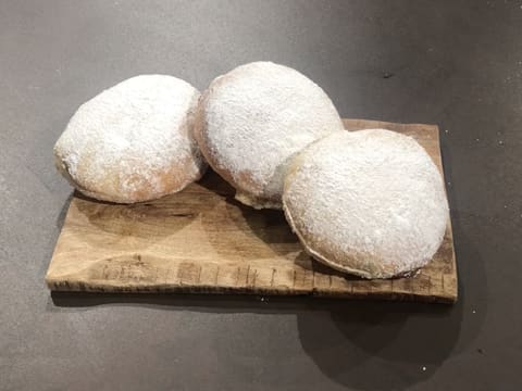 Obtention de trois beignets fourrés de pâte à tartiner maison et saupoudrés de sucre glace, disposés sur leur plat de présentation