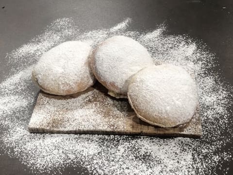 Obtention de trois beignets fourrés de pâte à tartiner maison et saupoudrés de sucre glace, disposés sur leur plat de présentation