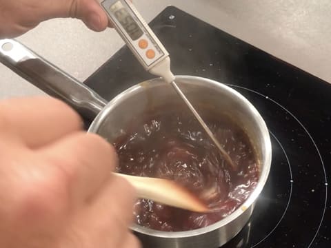 Prise de la température de la sauce caramel à la framboise dans la casserole, à l'aide d'un thermomètre à sonde qui affiche 105,3°C