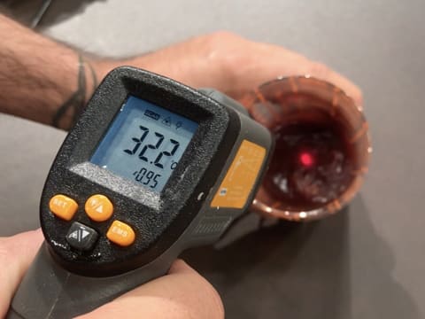 Prise de la température de la sauce caramel à la framboise dans le verre doseur, à l'aide d'un thermomètre à sonde qui affiche 32,2°C