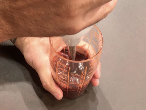 La préparation au caramel et à la framboise est mixée dans le verre doseur à l'aide d'un mixeur plongeant