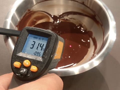 Prise de la température de la préparation chocolatée dans le cul de poule à l'aide d'un thermomètre à visée laser qui affiche 31,4°C