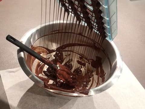 Le moule chocolat demi sphère est retourné au dessus du cul de poule qui contient le chocolat noir tempéré, et l'excédent de chocolat s'écoule du moule