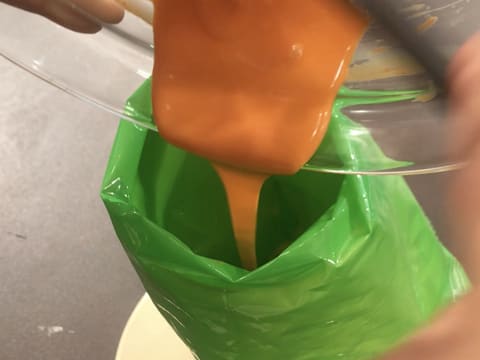 Le chocolat blanc coloré en orange est versé dans une poche à douille