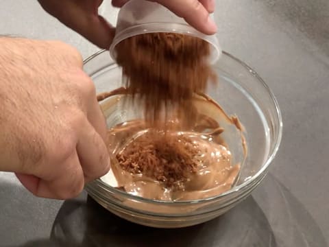 Ajout de la noix de coco sablée dans la préparation chocolatée qui se trouve dans le saladier