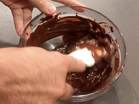 Mélange du chocolat noir fondu dans le saladier, à l'aide de la spatule type maryse