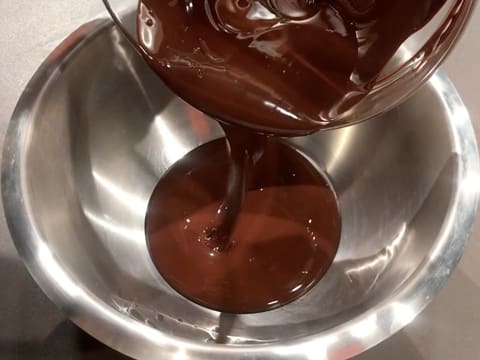 Le chocolat noir fondu est débarrassé dans un cul de poule en inox