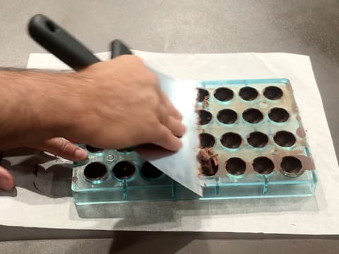 Le dessus de la plaque à chocolat demi-sphère est raclé avec la spatule à chocolat