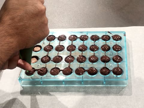 Le chocolat tempéré est poché sur les disques de croustillant coco dans les demi-sphères de la plaque à chocolat