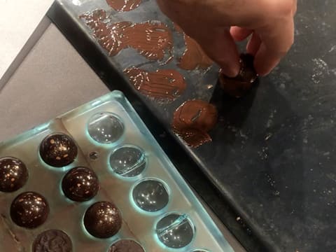 La surface plane d'une demi-sphère en chocolat est fondue sur une plaque à pâtisserie tiède