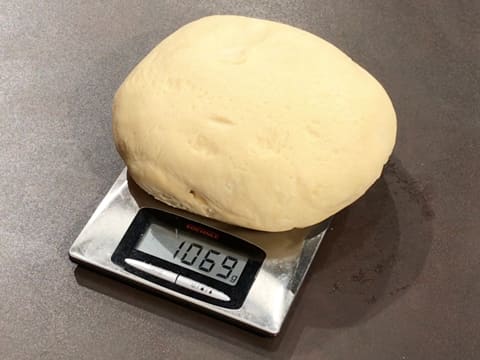 La boule de pâte à brioche est placée sur une balance de cuisine électronique, sur le plan de travail