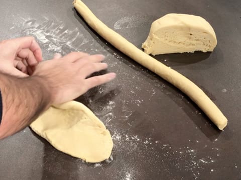 Le deuxième pâton de pâte est aplati avec la paume de la main sur le plan de travail fariné