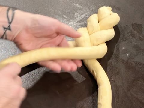 Formation d'une tresse sur le plan de travail avec les trois boudins de pâte à brioche