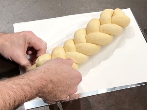 La brioche tressée est placée sur une plaque à pâtisserie recouverte d'une feuille de papier sulfurisé