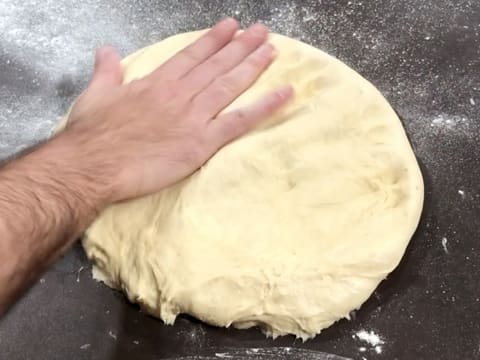 La pâte est aplatie avec la main sur le plan de travail