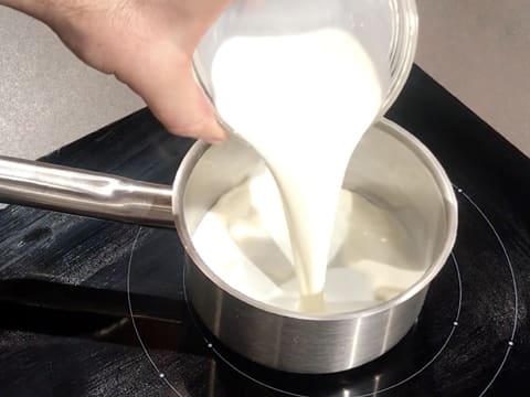 Le lait est versé dans une petite casserole qui est placée sur une plaque de cuisson