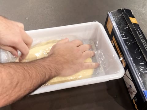 La pâte à brioche qui est dans le bac alimentaire, est filmée au contact avec une feuille de papier film