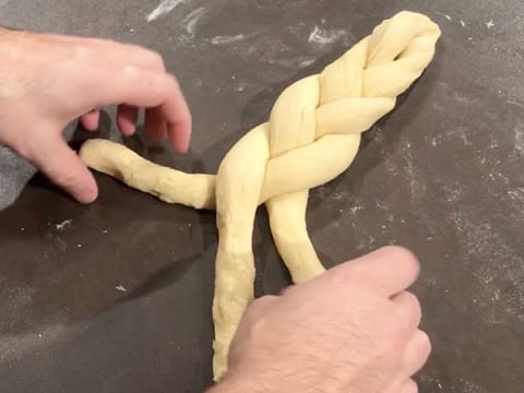 Une tresse est formée avec les trois boudins de pâte sur le plan de travail