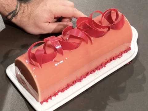 Obtention de la bûche glacée et décorée avec des éclats de framboise croustillants à sa base