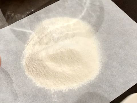 La farine et la levure chimique sont tamisées sur la feuille de papier sulfurisé