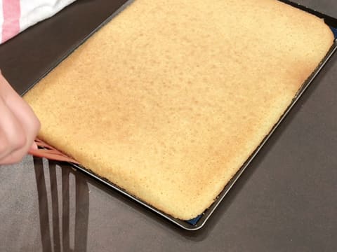 Le bord du biscuit madeleine est soulevé à l'aide d'une spatule