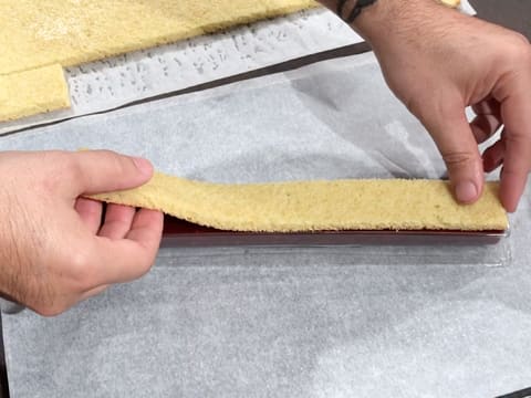 La bande de biscuit est déposée sur le confit de framboise, dans le moule insert à bûche