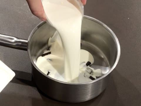 Ajout du lait sur la crème fleurette et les bâtonnets de vanille, dans la casserole