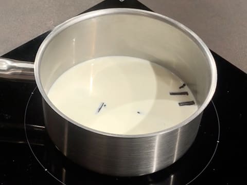 La casserole contenant le lait, la crème liquide et les bâtonnets de vanille est placée sur la plaque de cuisson
