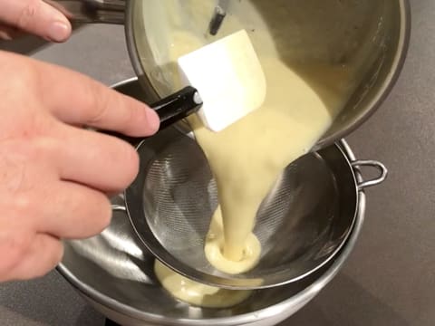 La crème est filtrée dans une passoire fine au-dessus d'un cul de poule