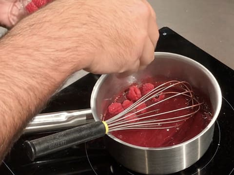 Ajout de framboises fraîches dans la casserole contenant la purée de framboise