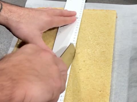 Découpe d'une bande de biscuit avec la règle graduée et un couteau