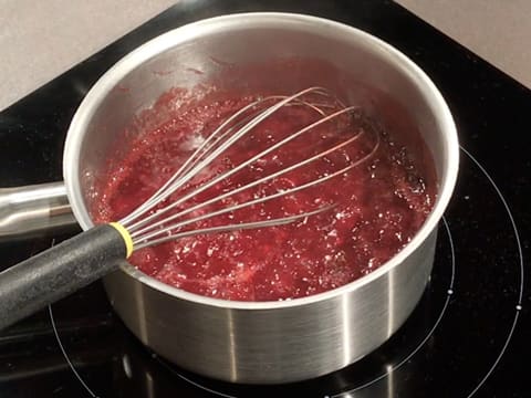 La purée de framboise est fouettée et en ébullition dans la casserole