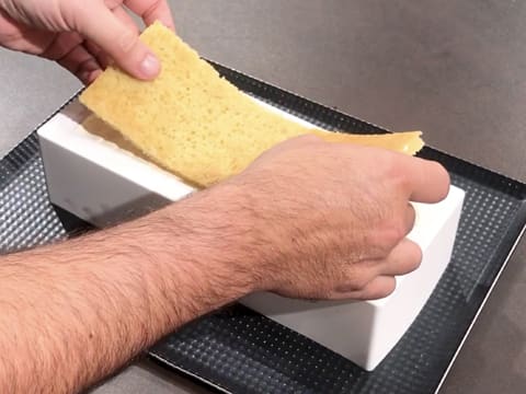 La bande de biscuit madeleine est déposée sur la mousse suprême vanille Tahiti, dans le moule à bûche en silicone