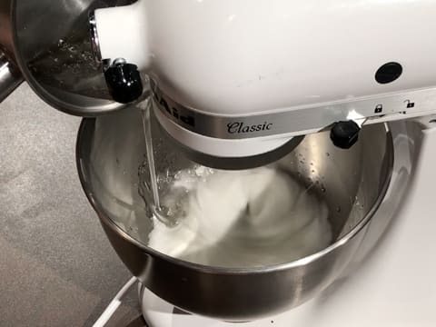 Le sirop est versé sur les blancs en neige, dans la cuve du batteur