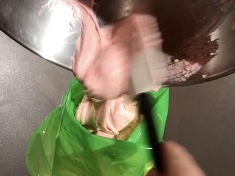 La pâte à macarons rose est versée dans une poche à douille