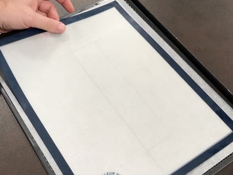 Un tapis de cuisson silicone est posé sur la feuille de papier sulfurisé