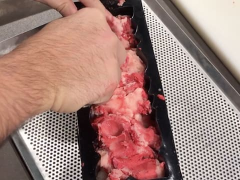 Du sorbet litchi et framboise est étalé dans le moule à bûche silicone, sur toute la longueur