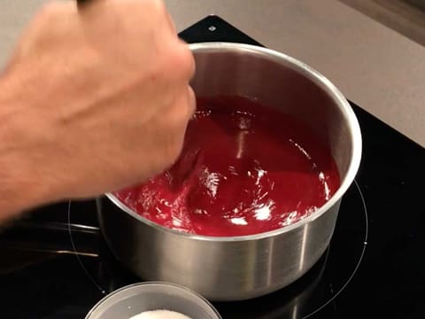 Mélange de la purée de framboise et du sucre en poudre avec le fouet, dans la casserole