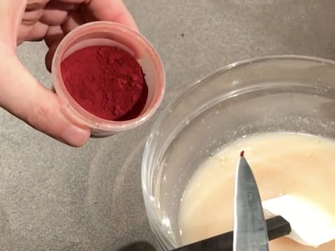 Ajout d'une pointe de colorant rouge dans le saladier, sur la préparation au litchi