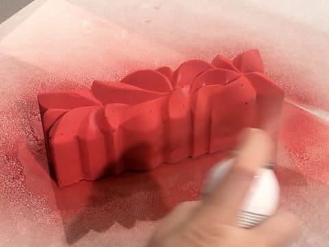 Pulvérisation du colorant en spray rouge sur le pourtour de la bûche glacée