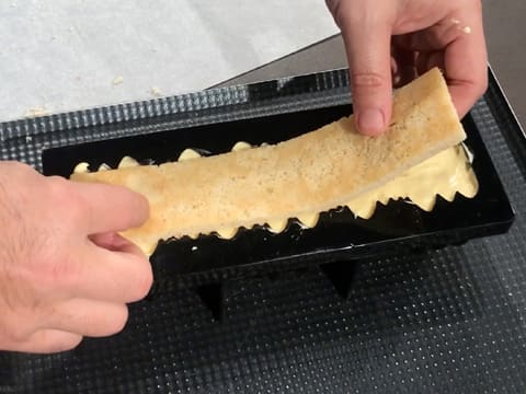 La bande de biscuit financier est placée dans le moule à bûche silicone sur la mousse Inspiration passion