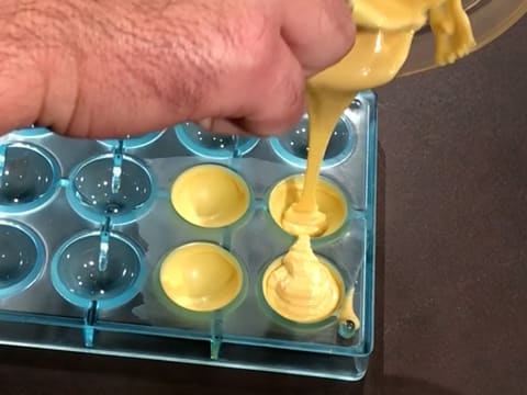 Une deuxième couche de chocolat fondu est versée sur chocolat cristallisé dans les quatre empreintes du moule demi sphère