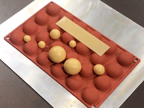 Les sphères en chocolat et la bande de chocolat sont placées sur l'envers d'un moule silicone demi sphère