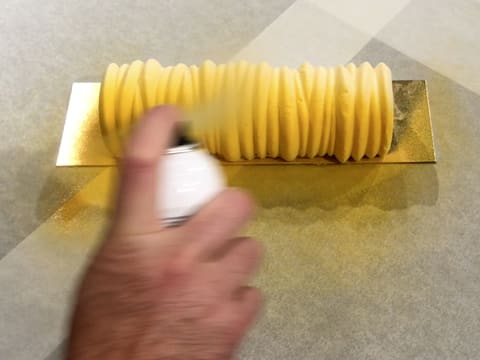 Pulvérisation du colorant en spray effet velours jaune sur le premier côté de la bûche