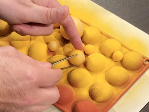 Une sphère en chocolat est retournée avec une pince à dresser