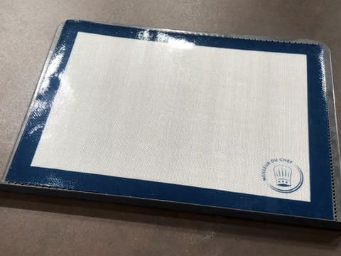 Un tapis de cuisson silicone est posé sur une plaque de cuisson perforée
